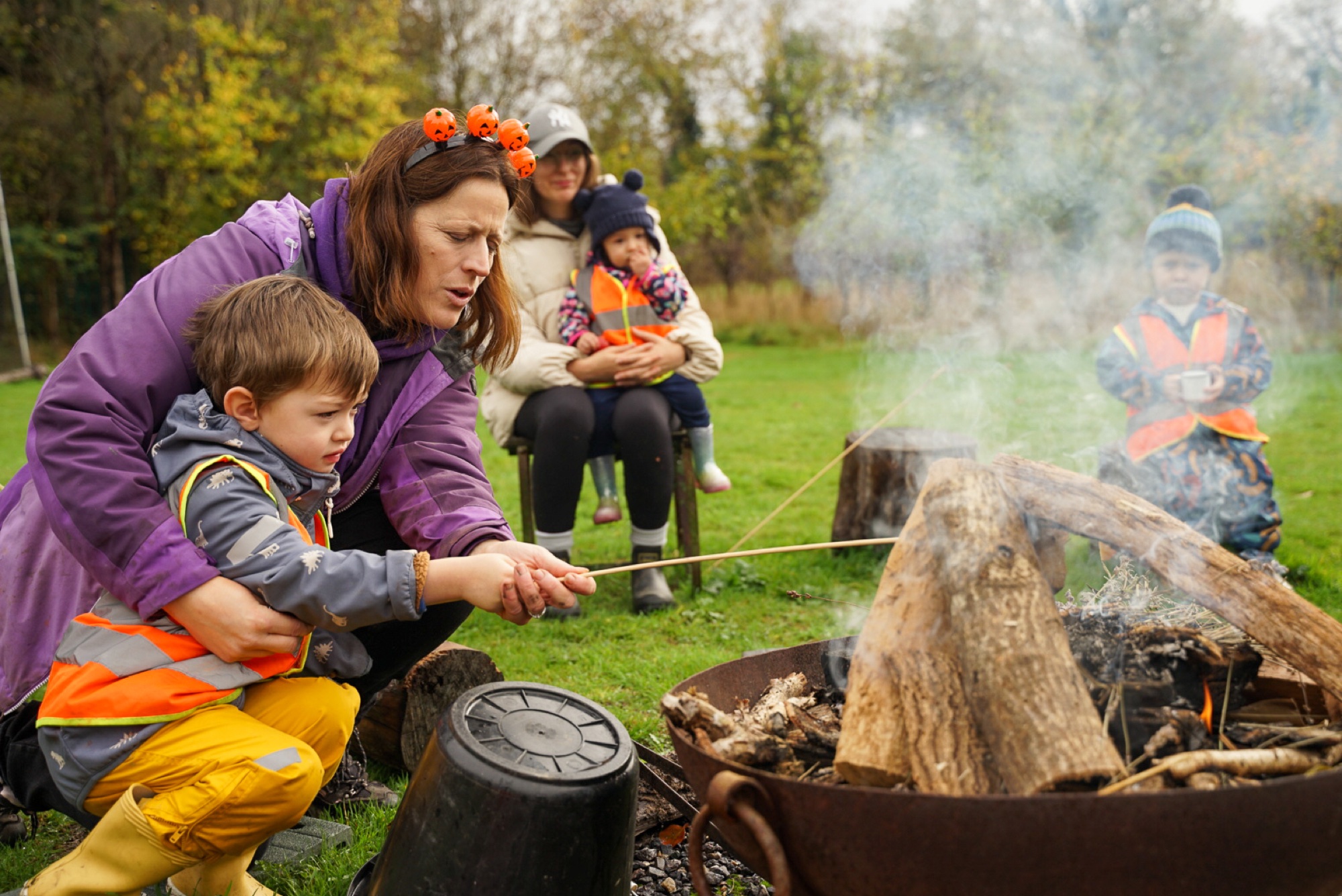 Family toasting marshmallows around a campfire on an autumn day in Buckinghamshire